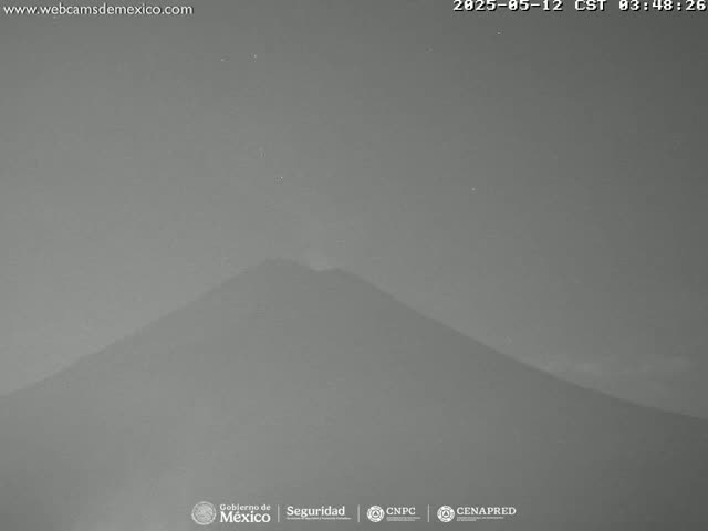 A dark, hazy night scene shows a large, silhouetted mountain.