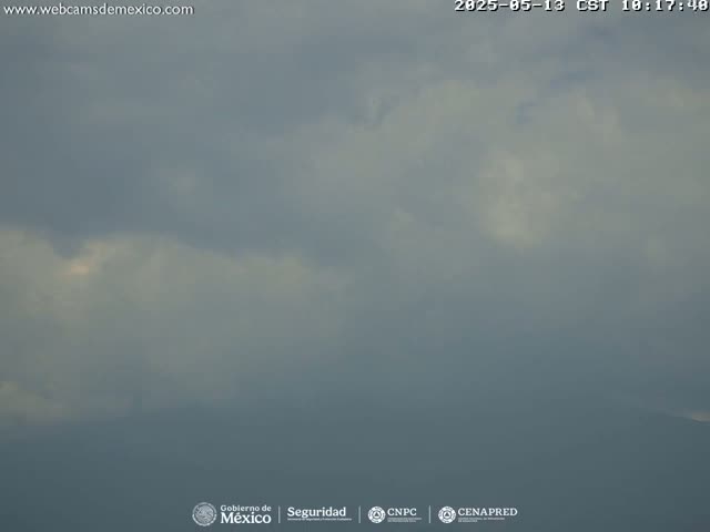 A mostly cloudy sky obscures a distant mountain range under an overcast sky.