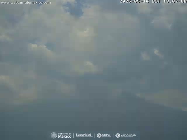 A hazy, overcast sky with scattered clouds obscures a distant, indistinct landscape.