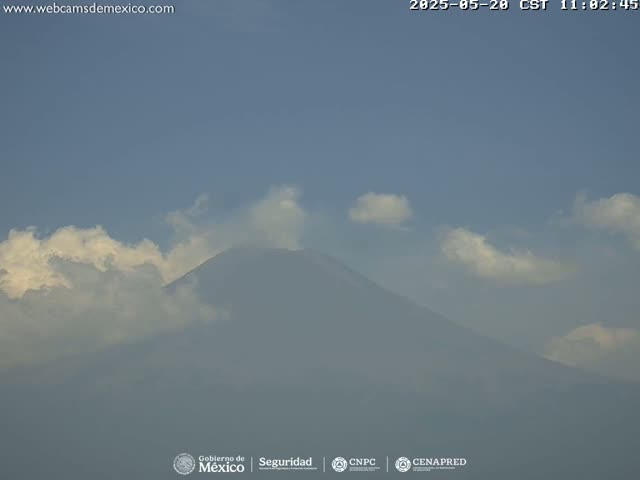 A hazy, partly cloudy sky partially obscures a large, dark mountain.