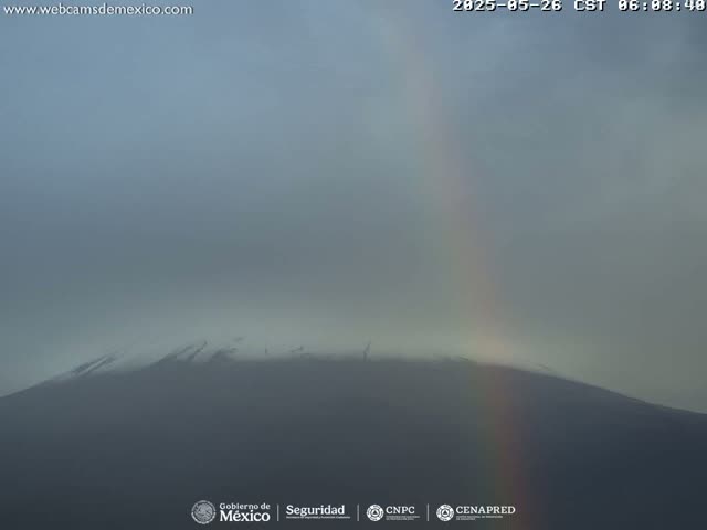 A hazy mountain peak is visible beneath a faint rainbow in overcast conditions.