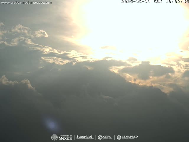 A partly cloudy sky with the sun shining through breaks in the clouds.