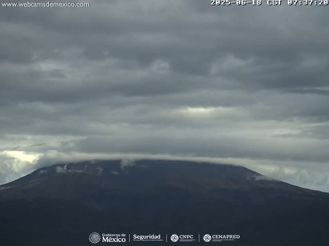 A dark, overcast sky covers a mountain peak shrouded in low clouds.