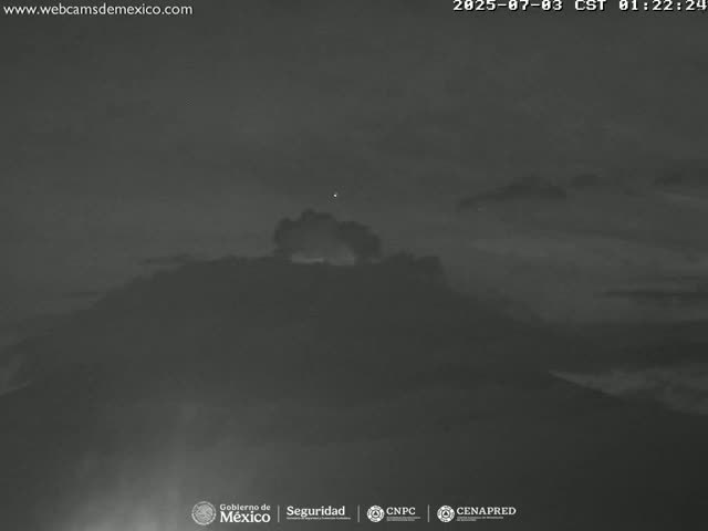 A dark, hazy night scene shows a mountain range under a cloudy sky.