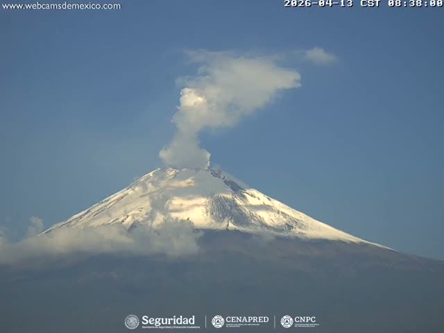 A large volcano emits a plume of smoke or ash against a clear, star-filled night sky.