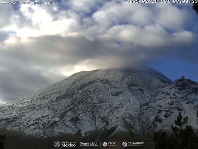 A snow-dusted mountain is partially obscured by a cloudy sky.