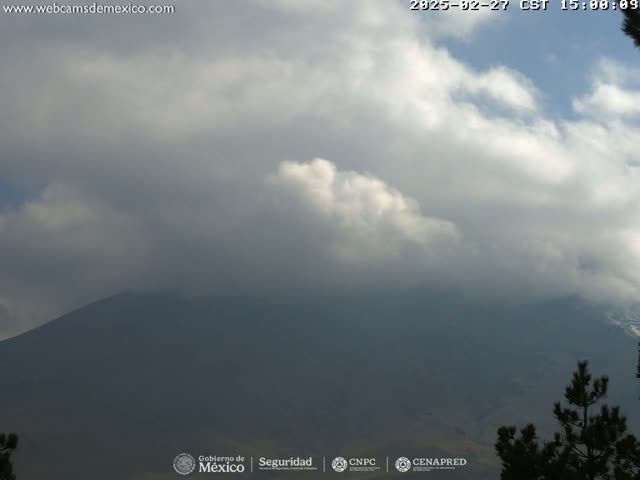 A mostly cloudy sky hangs over a dark, distant mountain range partially obscured by fog or mist.