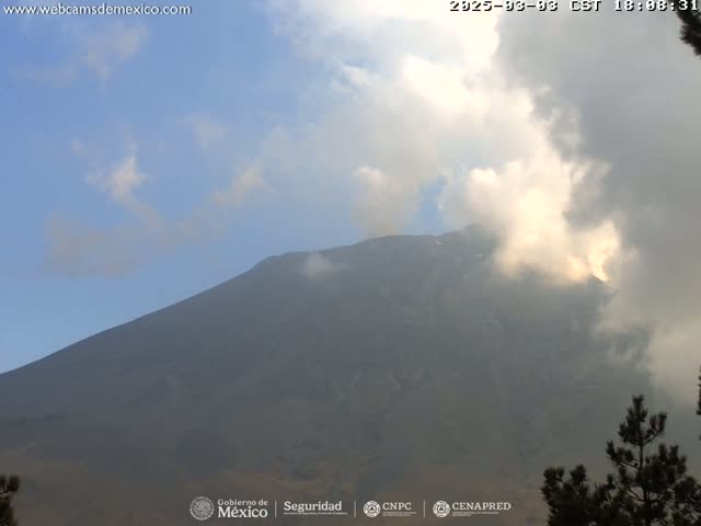 A large, dark mountain is partially obscured by a hazy, cloudy sky.