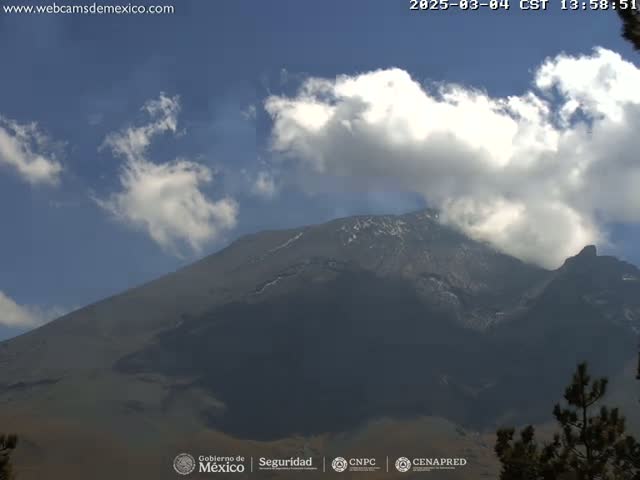 A partly cloudy sky is visible over a large, dark mountain with some snow near the peak.