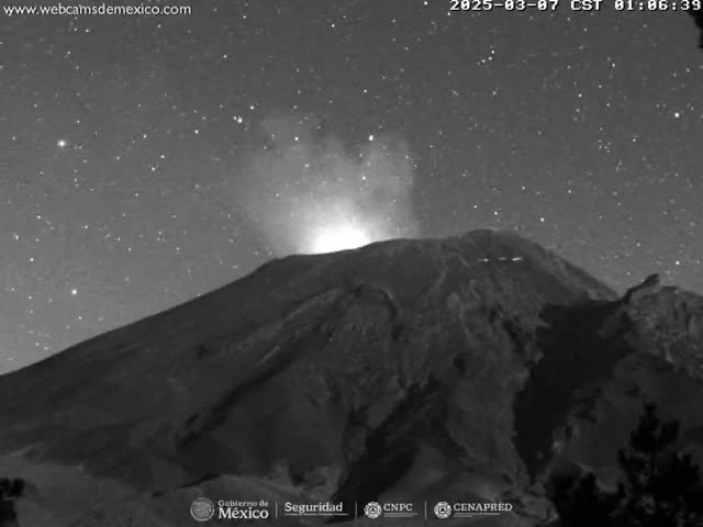 A volcano erupts under a clear, starry night sky.