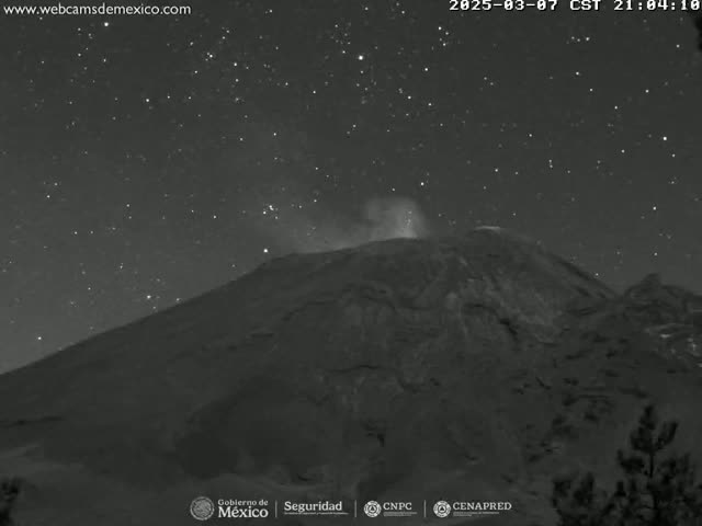 A nighttime, starlit view of a volcano emitting a small plume of smoke.