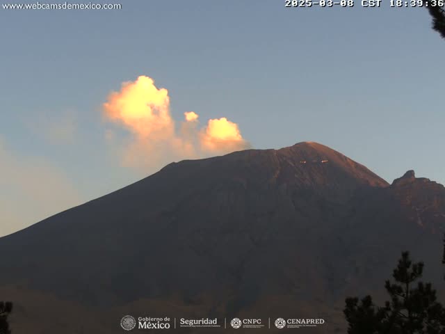 A large, dark mountain is partially illuminated by the setting sun, with a small amount of light-orange colored clouds above it.