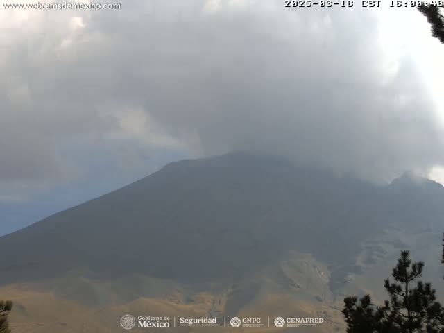 A large, dark mountain is partially obscured by a hazy, overcast sky.