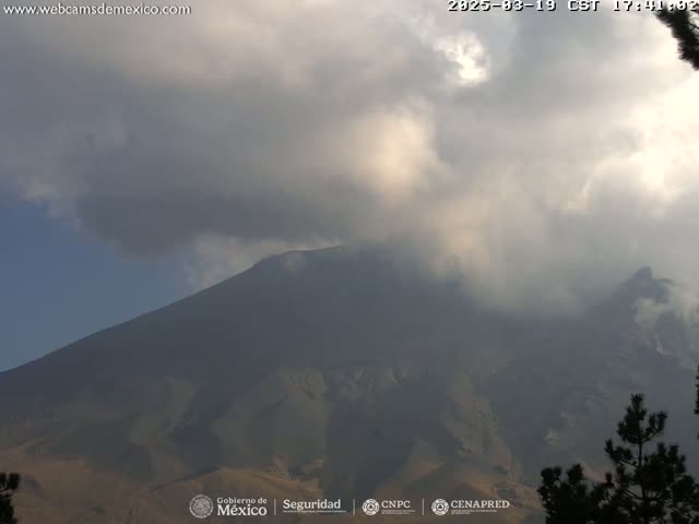 A large, dark mountain is partially obscured by a cloudy sky.