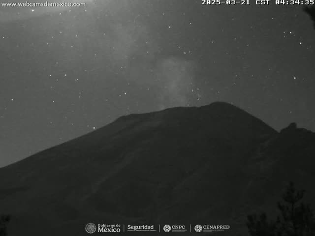 A dark mountain is silhouetted against a night sky filled with stars and a faint Milky Way.