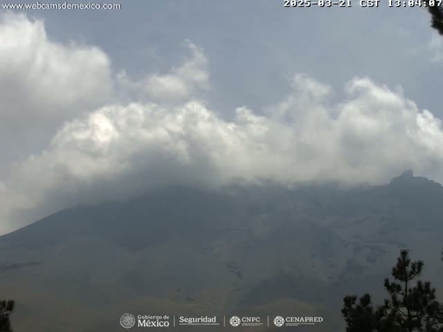 A partly cloudy sky obscures a view of a large, dark mountain range.