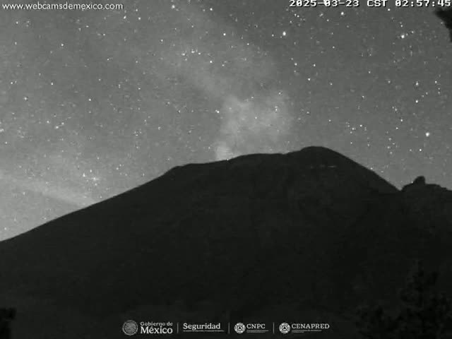 A dark mountain is silhouetted against a night sky filled with stars and a faint milky way.
