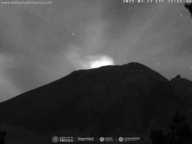 A nighttime, grayscale image shows a volcano erupting under a mostly clear, starry sky.