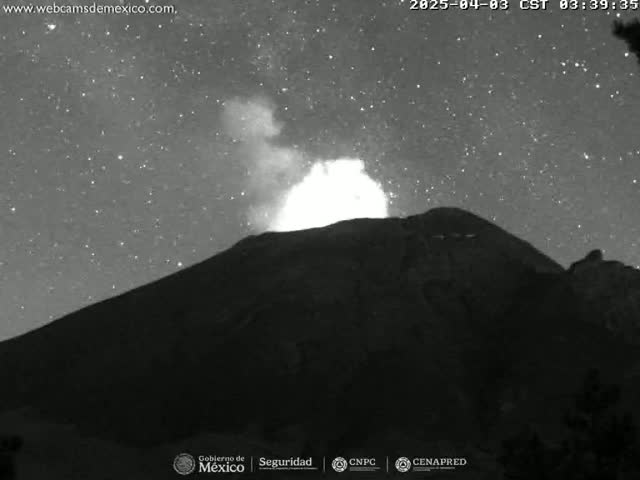 A volcano erupts under a starry night sky.