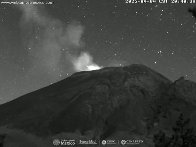 A nighttime, starlit view of a volcano emitting a plume of smoke and ash under a clear sky.