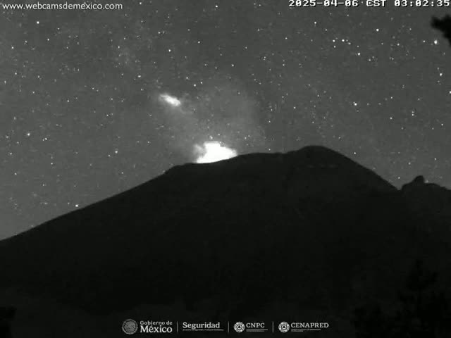 A volcano erupts under a clear, starry night sky.