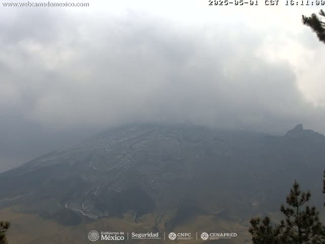 A hazy, overcast view shows a large, dark mountain range extending to the horizon.
