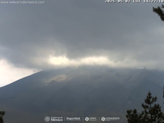 A large, dark mountain is partially obscured by an overcast sky with a break of light visible through the clouds.