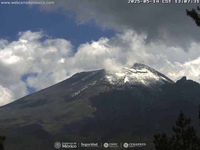 A snow-capped mountain is visible under a partly cloudy sky.