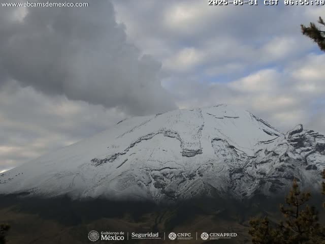 A snow-capped mountain is partially obscured by a cloudy sky.