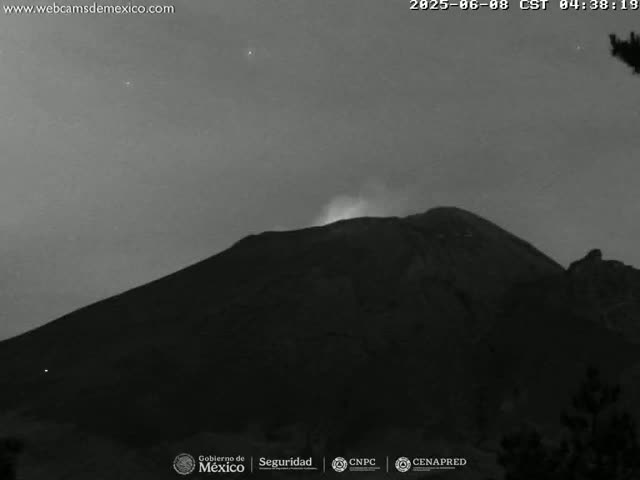 A dark, volcanic mountain is faintly illuminated under a night sky with a slight glow emanating from its peak.
