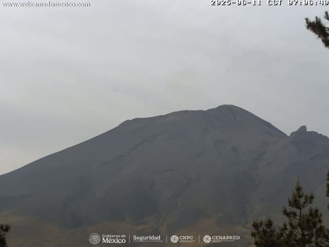 A large, dark-colored mountain is visible under a hazy, overcast sky.