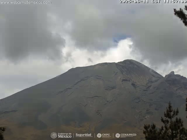 A large, dark-grey volcano is partially obscured by an overcast sky.