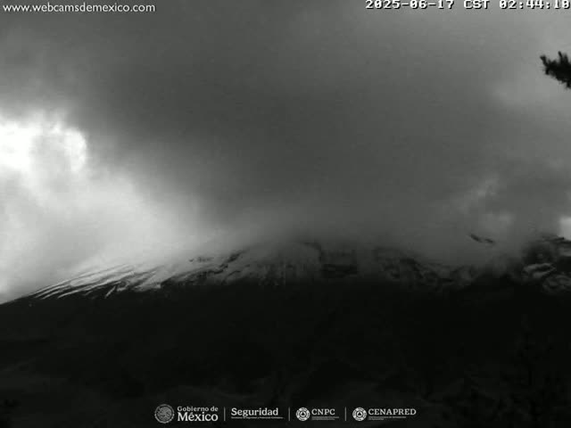 A snow-capped mountain is partially obscured by heavy, overcast skies.