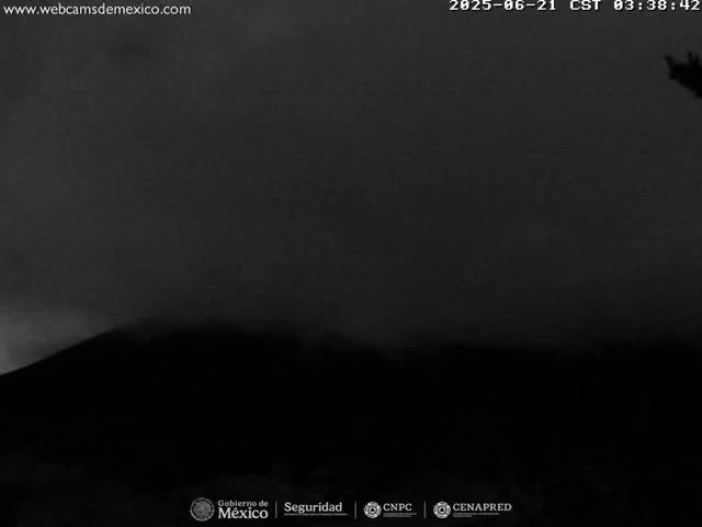 A dark, possibly overcast, nighttime scene shows a silhouetted hill or mountain.