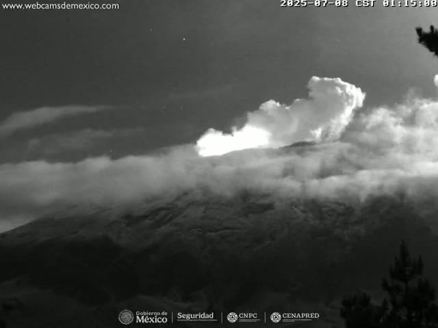 A grayscale image shows a volcano erupting under a cloudy night sky.