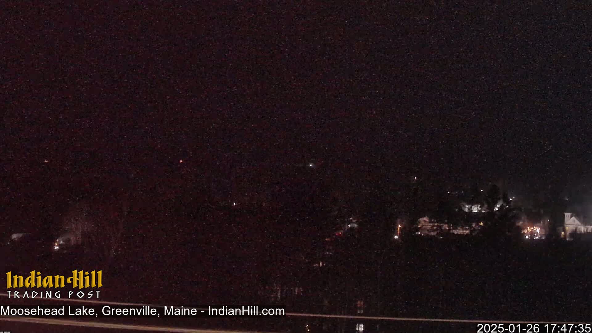 A nighttime long shot shows a dark, sparsely-lit landscape with a few faint lights visible in the distance.
