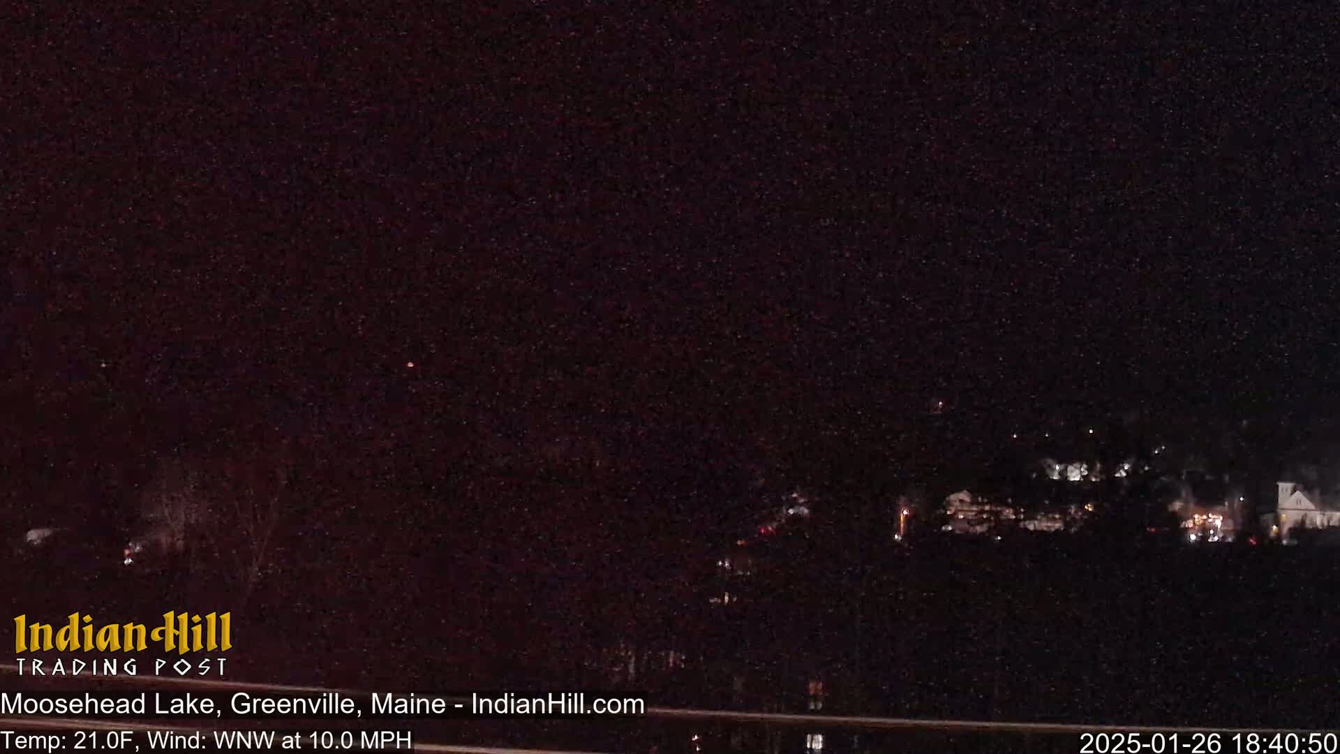 A nighttime long shot shows a dark landscape with a few distant lights, under a dark, clear sky.