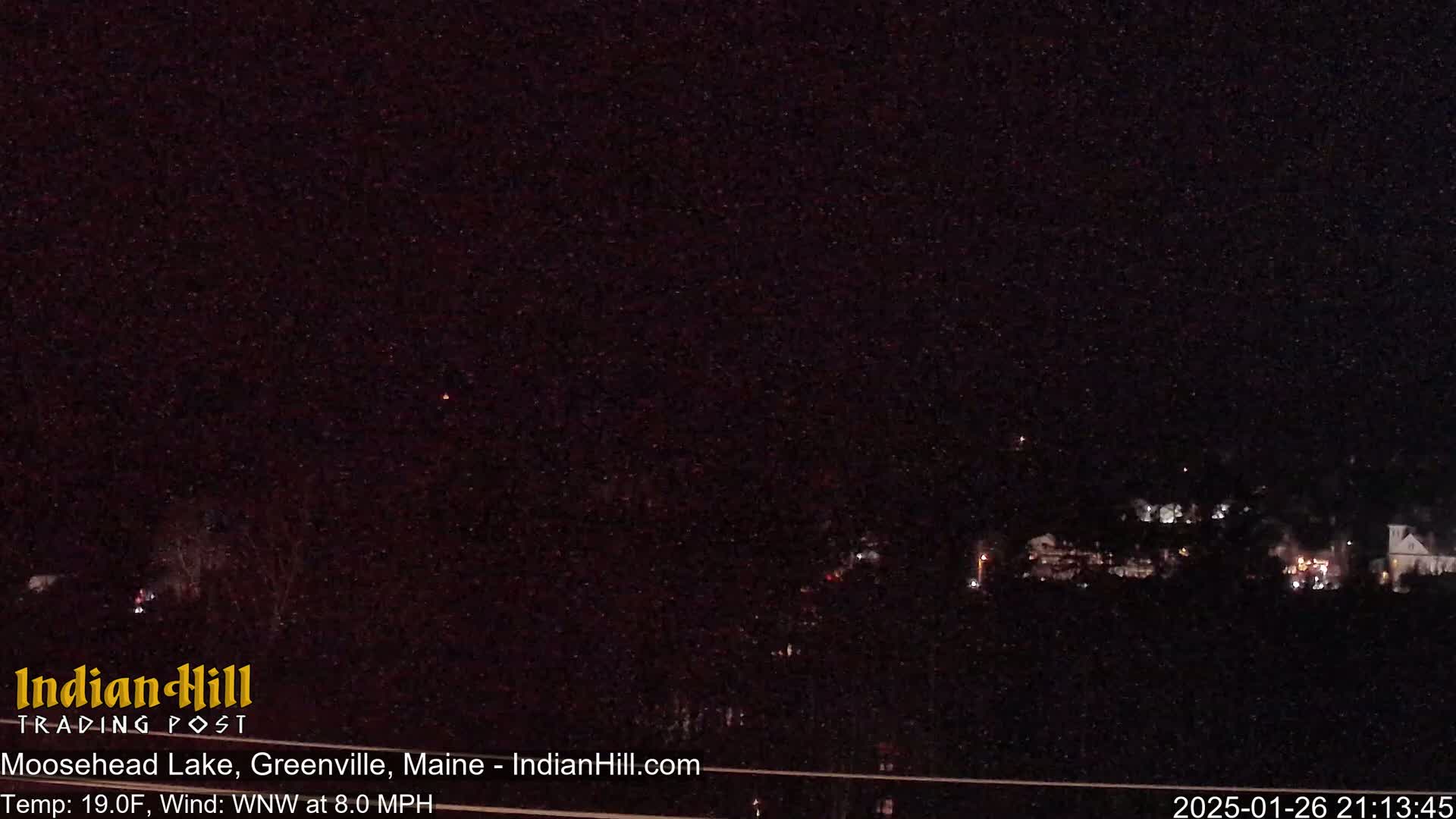 A nighttime long shot shows a dark, sparsely-lit landscape under a clear, starry sky, with a light wind blowing from the west-northwest at 8 miles per hour and a temperature of 19 degrees Fahrenheit.