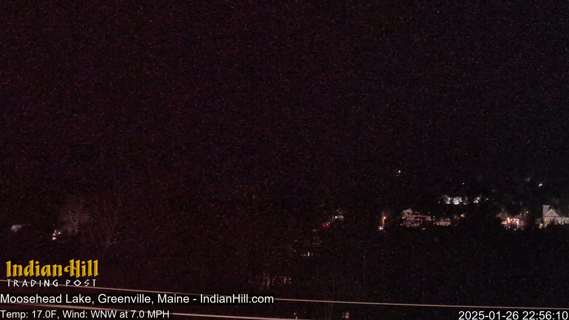 A nighttime long shot shows a dark landscape with a few distant lights under a clear, dark sky.