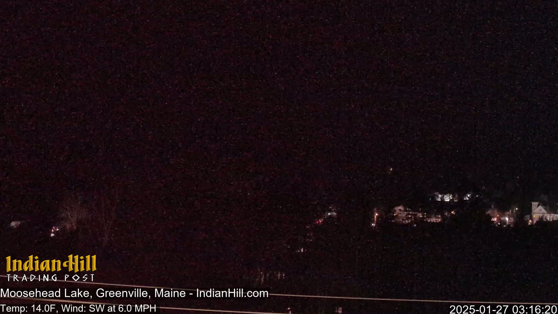A nighttime view of a small town with faint lights, under a dark, clear sky.