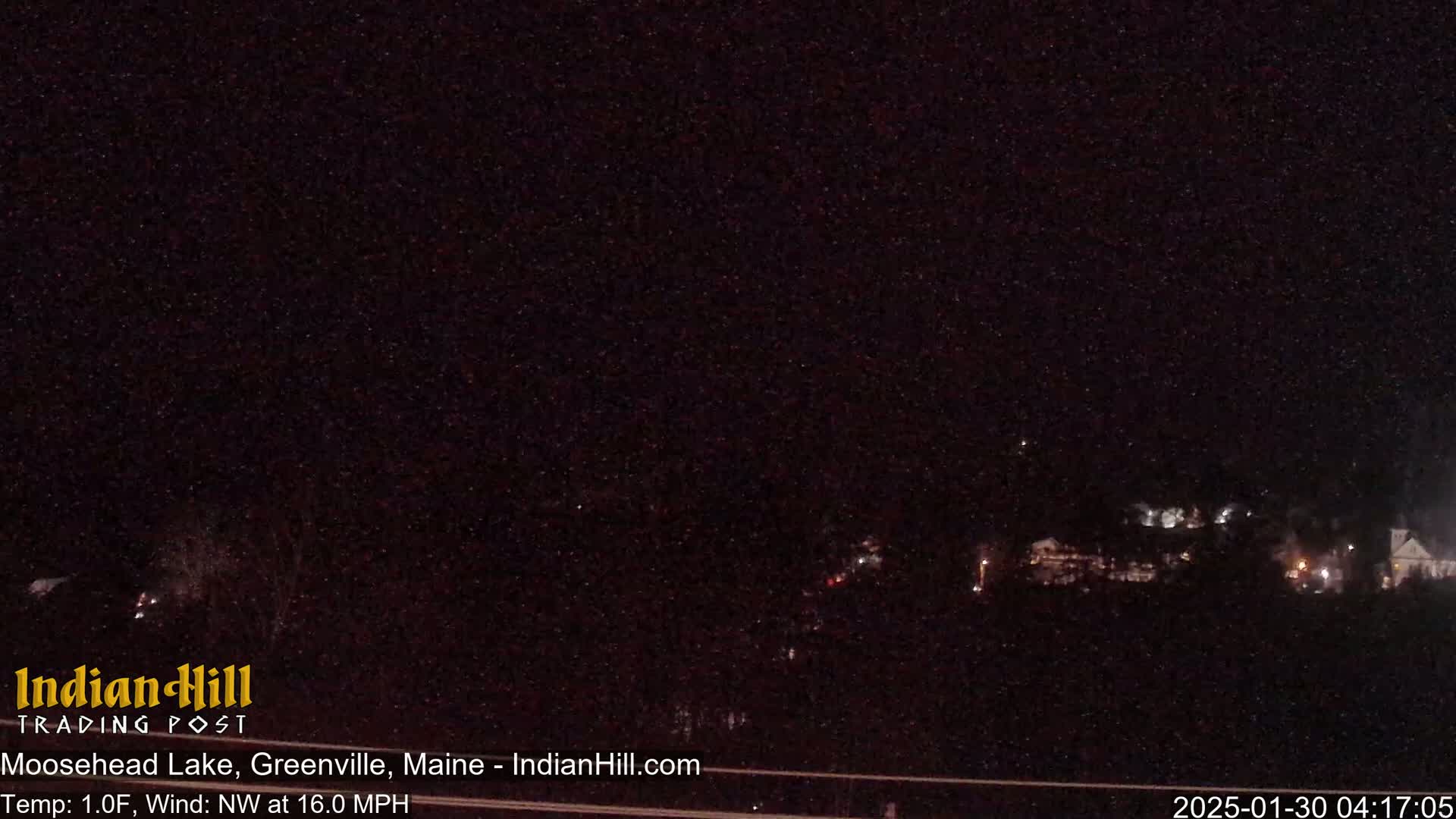 A nighttime, snow-covered landscape with a few distant lights visible under a dark, star-filled sky, with a northwest wind blowing at 16.0 mph and a temperature of 1 degree Fahrenheit.