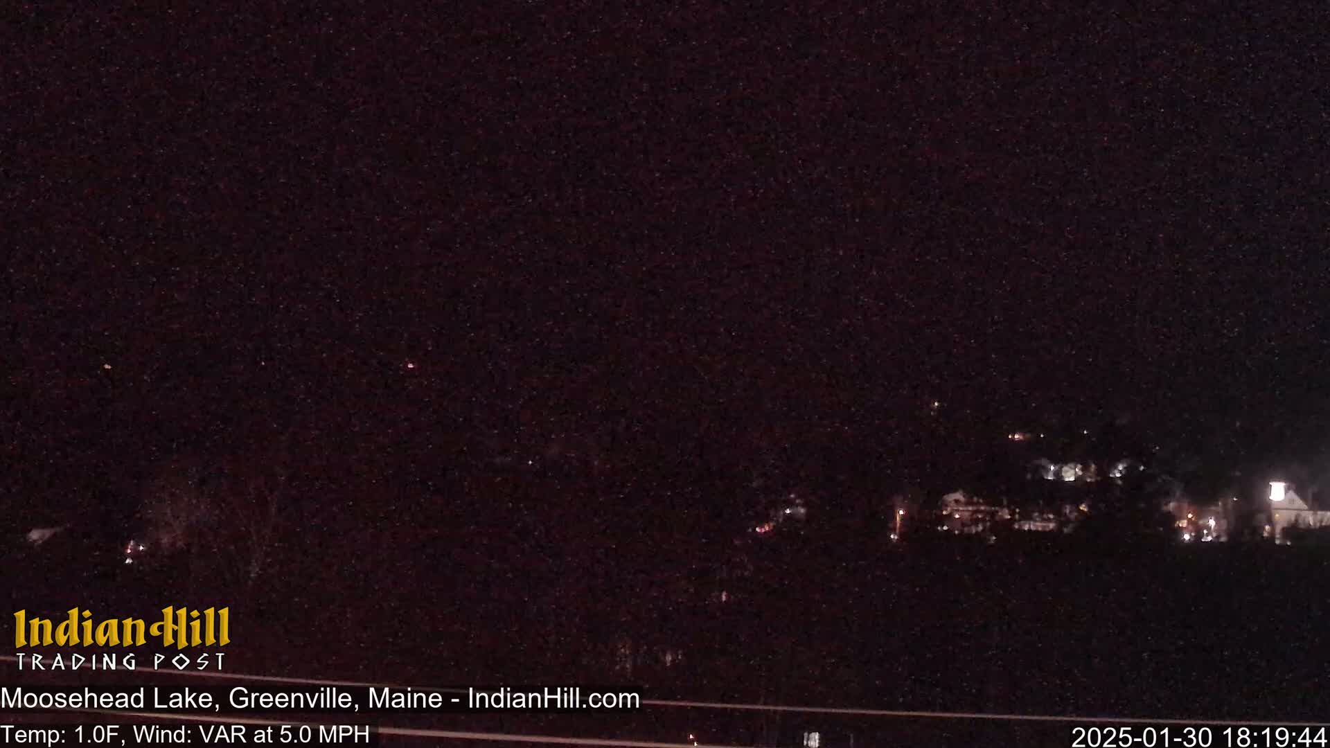A nighttime long shot of a dimly lit town under a dark, clear sky.