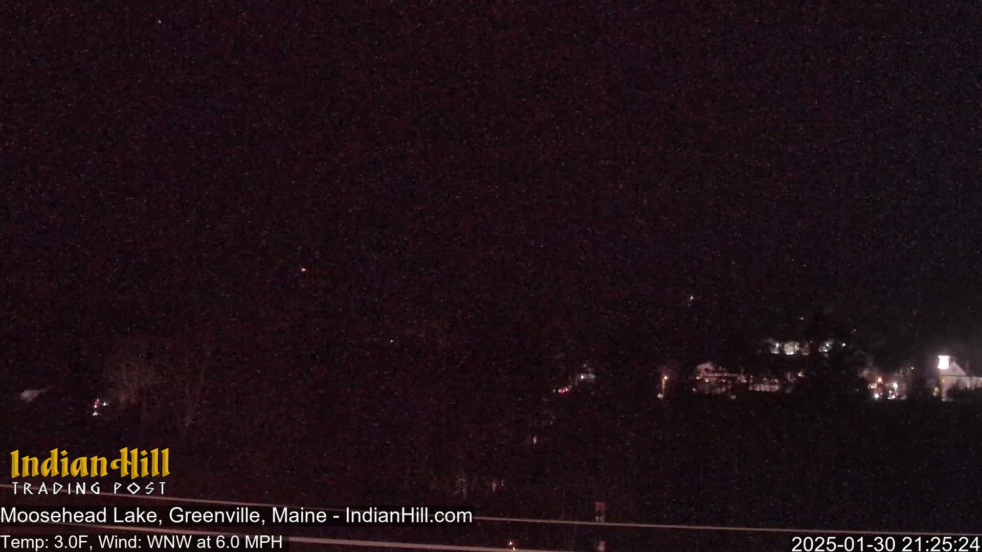 A nighttime view of a dark, sparsely lit landscape under a starlit sky, with a slight wind.