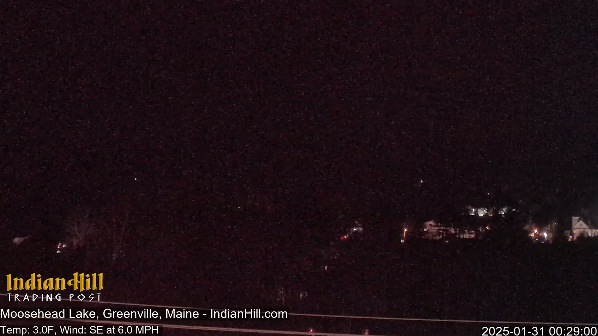 A nighttime long shot shows a dark landscape with a few distant lights under a dark, possibly snowy sky.
