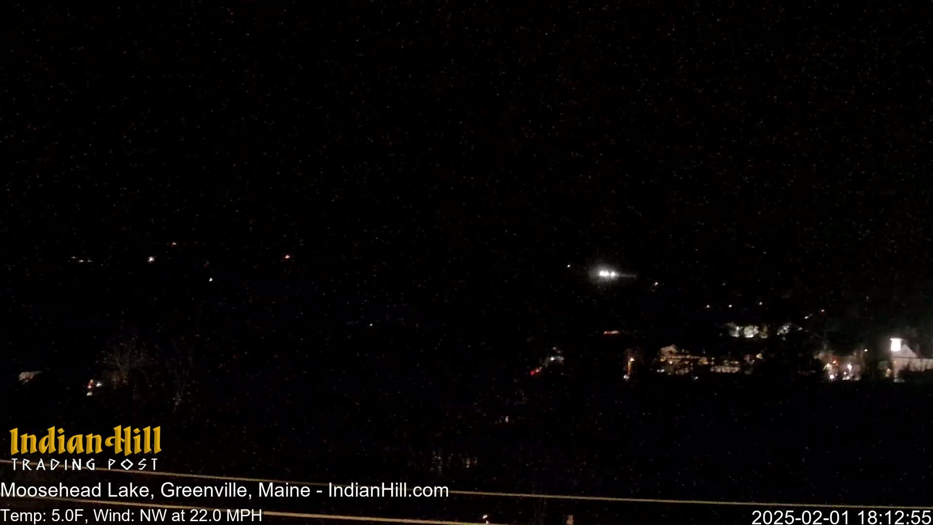 A nighttime view of a town with scattered lights under a dark, clear sky, with a northwest wind at 22 mph and a temperature of 5 degrees Fahrenheit.