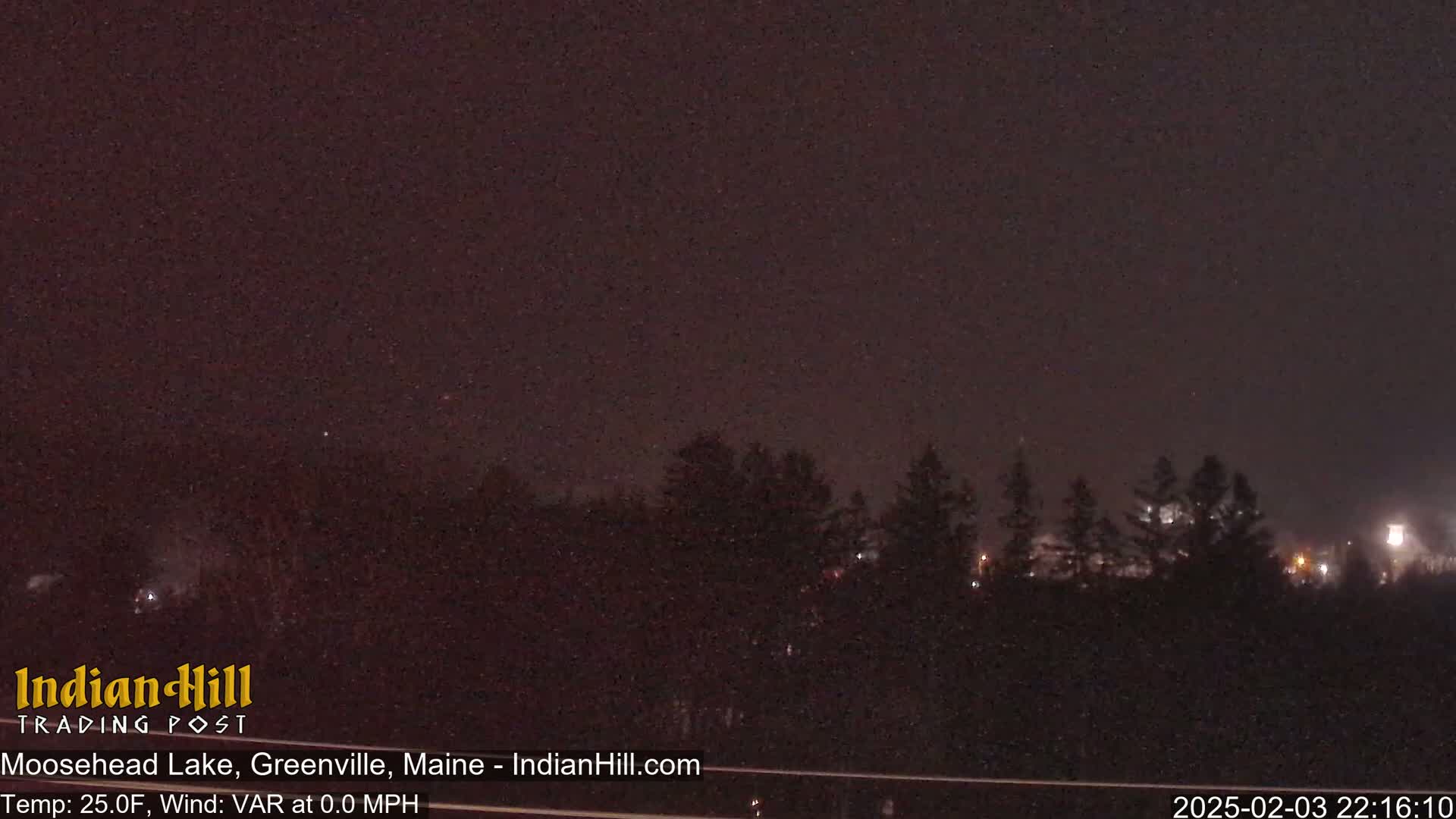 A nighttime view of a dark, treeline silhouetted against a dark sky.