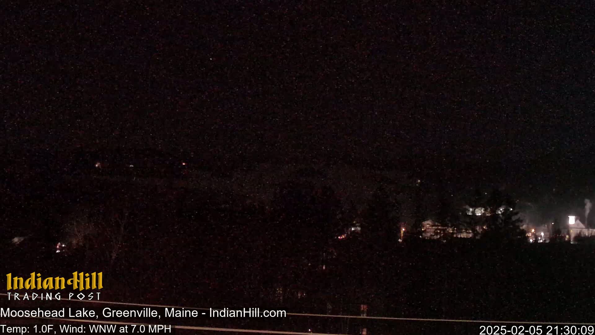 A nighttime long shot of a dimly lit town under a clear, starry sky.
