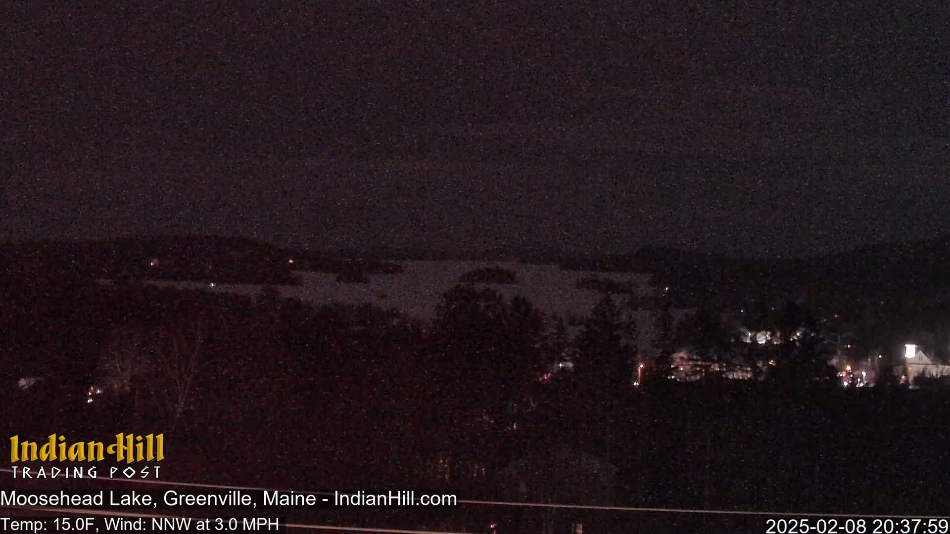 A nighttime view of a lake and a town, with a dark sky and a temperature of 15°F, and a north-northwest wind.