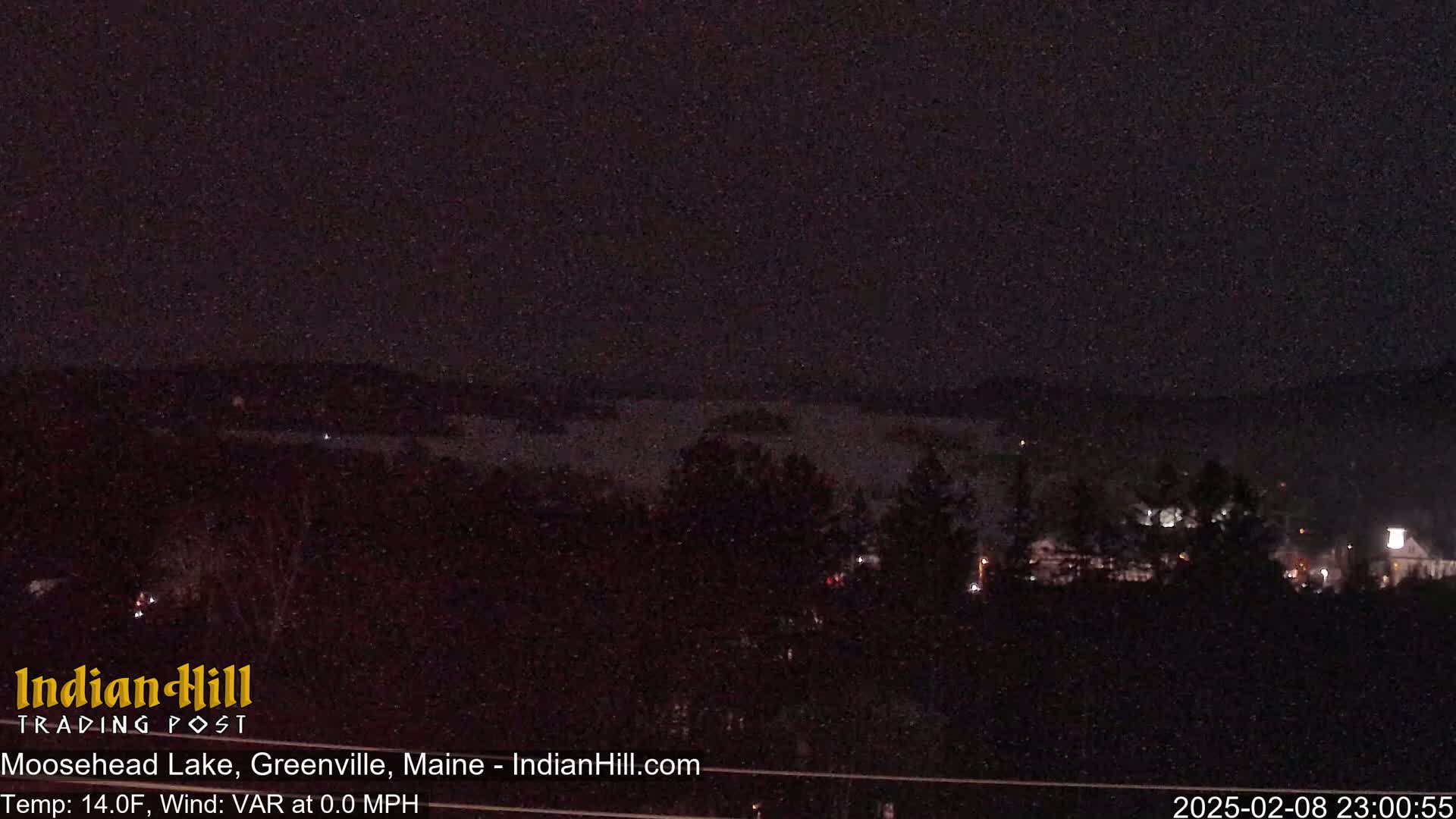 A nighttime, dark view of a lake and distant town, under a clear sky with a temperature of 14°F and no wind.