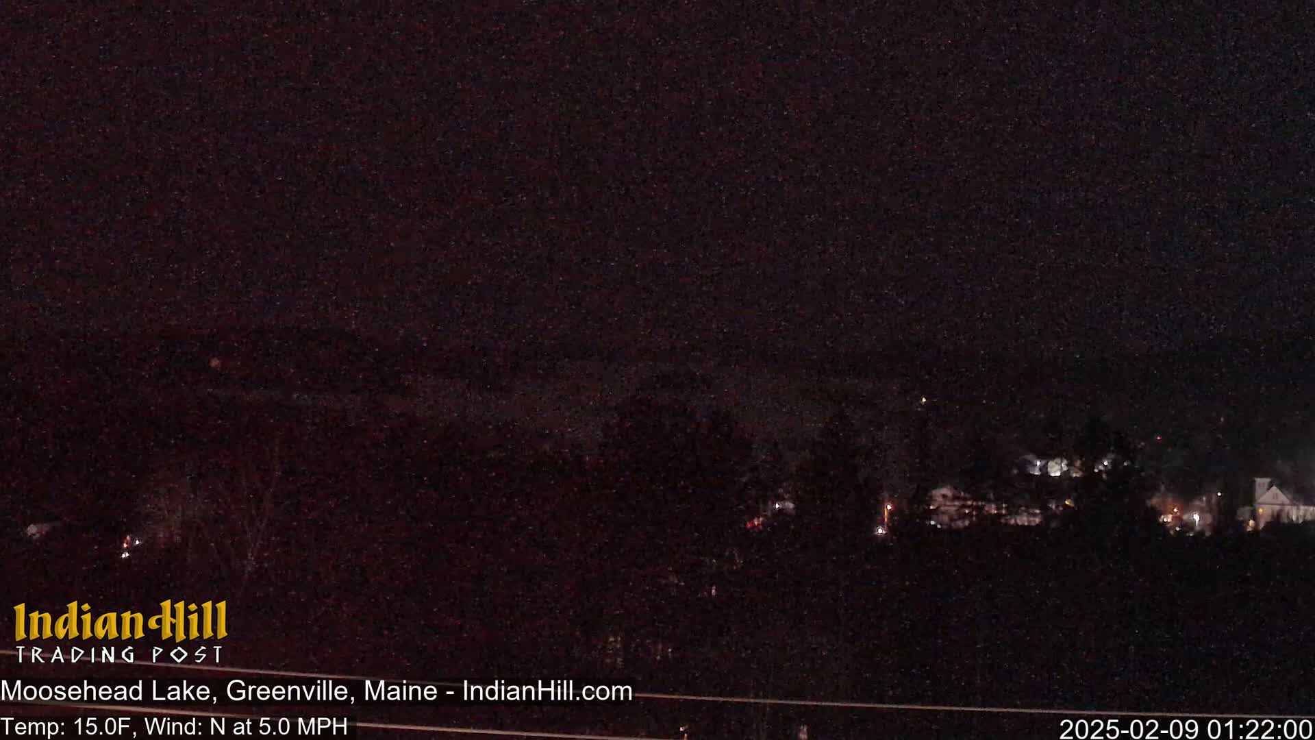 A nighttime long shot of a lake and town, under a dark sky with a temperature of 15 degrees Fahrenheit and a north wind of 5 mph.
